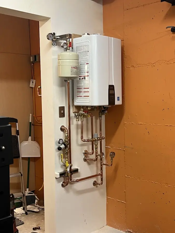 Plumbing technician inspecting water heater connections in Candia